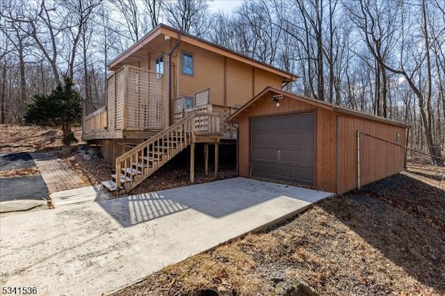 chalet / cabin featuring a detached garage, stairway, concrete driveway, and an outdoor structure