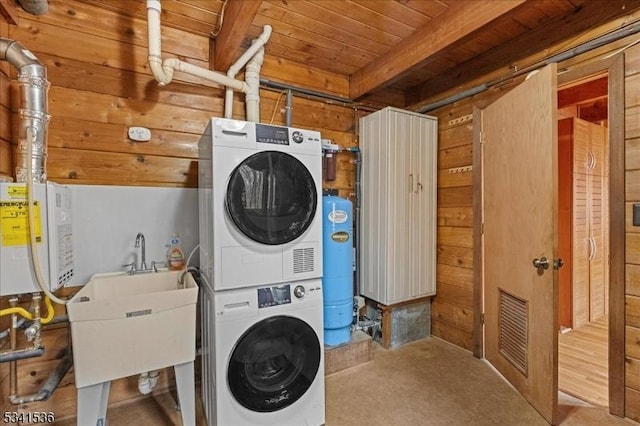 washroom with wooden walls, visible vents, wood ceiling, stacked washer / drying machine, and water heater