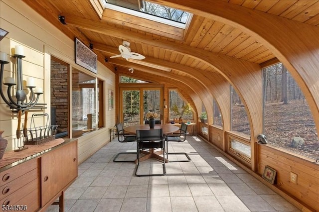 sunroom / solarium featuring vaulted ceiling with skylight and wooden ceiling