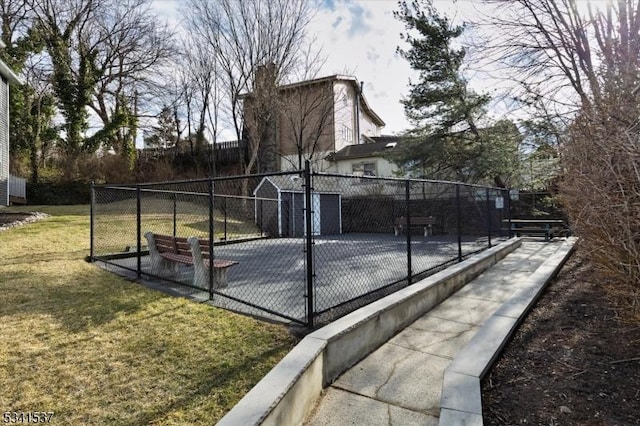 view of basketball court featuring a lawn and fence