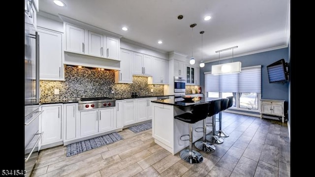 kitchen featuring dark countertops, premium range hood, appliances with stainless steel finishes, and a kitchen breakfast bar