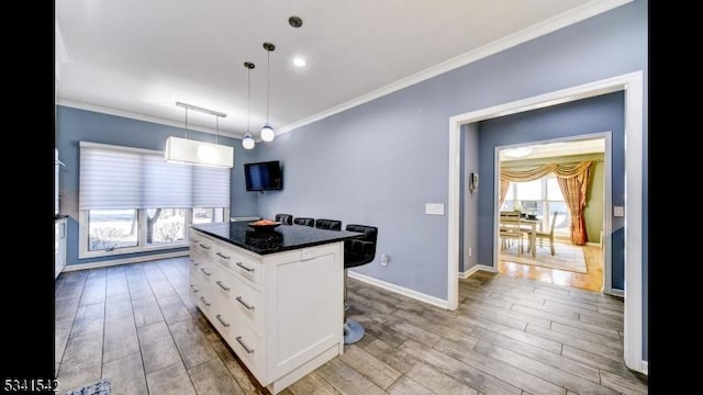 kitchen with ornamental molding, white cabinetry, baseboards, and wood finished floors