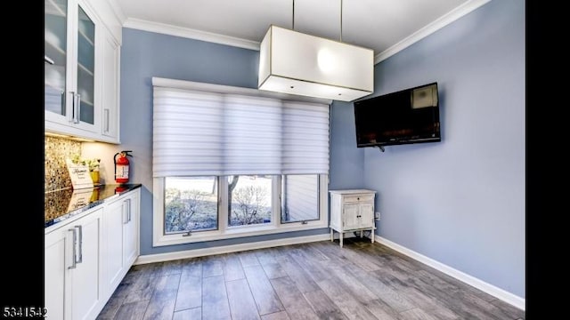 interior space with glass insert cabinets, white cabinetry, and crown molding