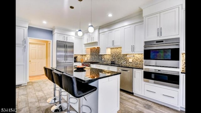 kitchen with a breakfast bar, hanging light fixtures, appliances with stainless steel finishes, a center island, and tasteful backsplash