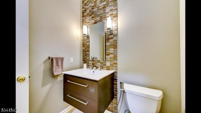 bathroom with toilet, vanity, and decorative backsplash