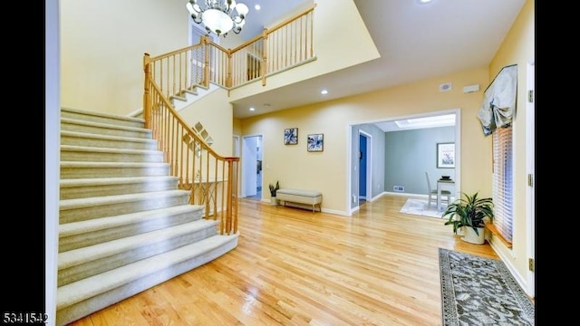 foyer with baseboards, stairs, a chandelier, and wood finished floors