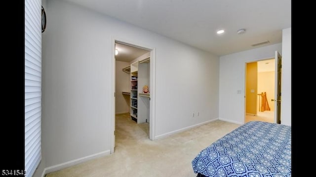 carpeted bedroom with a walk in closet, visible vents, baseboards, and recessed lighting