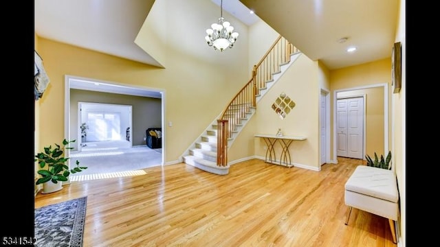 foyer featuring a chandelier, stairway, baseboards, and wood finished floors