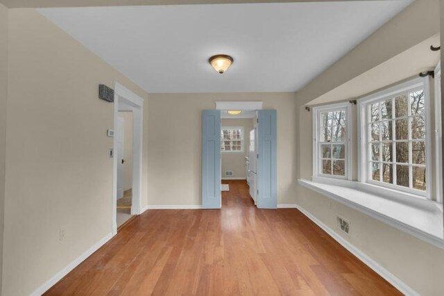 interior space with light wood finished floors, visible vents, and baseboards