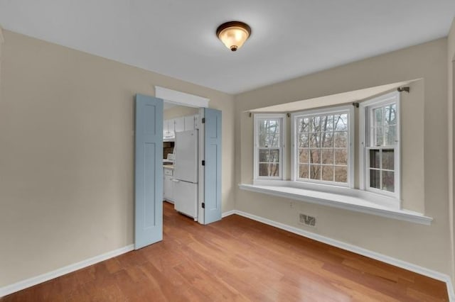 spare room with visible vents, baseboards, and wood finished floors