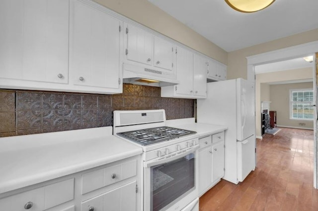 kitchen featuring tasteful backsplash, under cabinet range hood, light countertops, wood finished floors, and white appliances