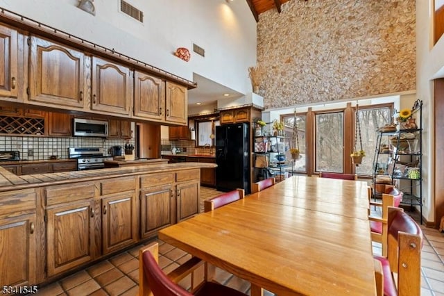 kitchen featuring tasteful backsplash, visible vents, tile counters, brown cabinets, and stainless steel appliances