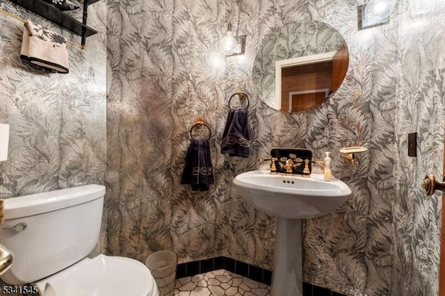 half bath with tile patterned floors, toilet, and wallpapered walls