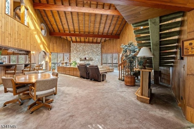 dining space with high vaulted ceiling, wooden ceiling, wooden walls, carpet flooring, and beam ceiling