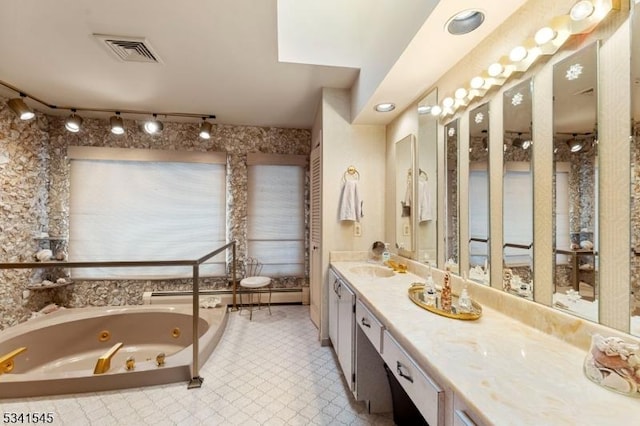 bathroom with a tub with jets, baseboard heating, vanity, and visible vents