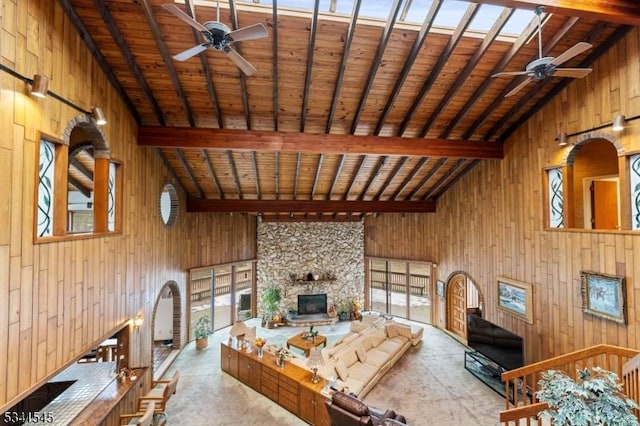 living room featuring wood walls, beam ceiling, and a ceiling fan