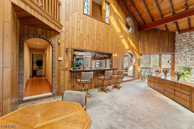 interior space with arched walkways, wooden walls, wood ceiling, beamed ceiling, and carpet