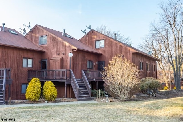 exterior space featuring stairs, a front lawn, and a wooden deck