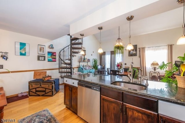 kitchen with dark stone counters, dishwasher, light wood-style flooring, pendant lighting, and a sink