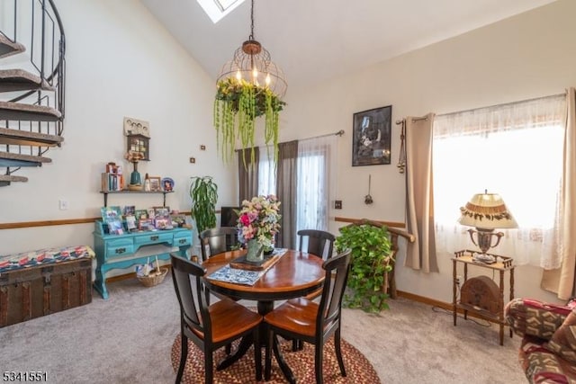 dining area with a skylight, stairway, an inviting chandelier, light carpet, and high vaulted ceiling