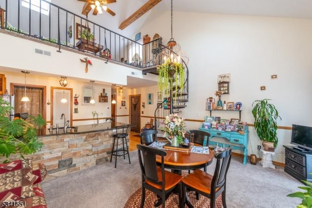 carpeted dining room featuring high vaulted ceiling, ceiling fan with notable chandelier, a sink, visible vents, and beamed ceiling