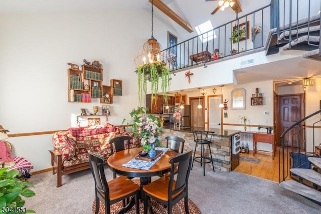 dining space featuring high vaulted ceiling, stairway, carpet flooring, and ceiling fan with notable chandelier