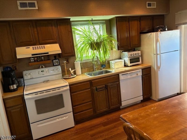 kitchen with white appliances, a sink, visible vents, and under cabinet range hood