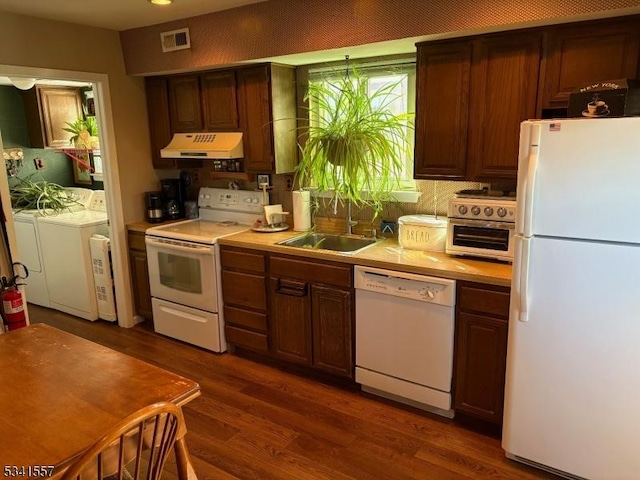 kitchen featuring white appliances, visible vents, light countertops, washer and dryer, and exhaust hood