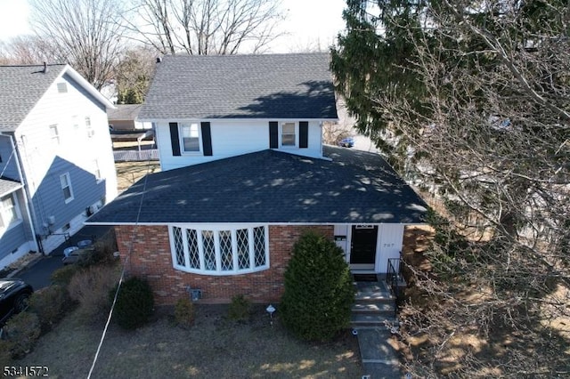 view of front of property with brick siding and roof with shingles