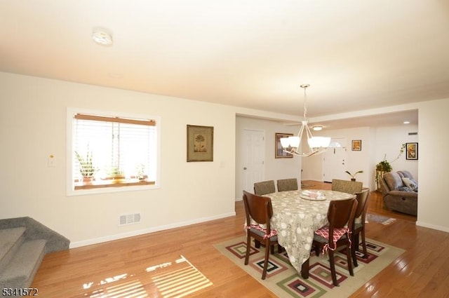 dining space featuring a chandelier, wood finished floors, visible vents, and baseboards