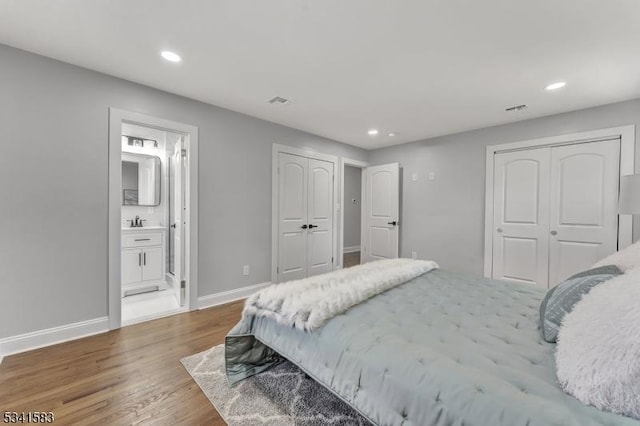 bedroom featuring recessed lighting, ensuite bathroom, a sink, wood finished floors, and baseboards