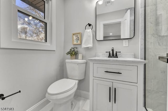 bathroom with visible vents, toilet, a tile shower, vanity, and baseboards