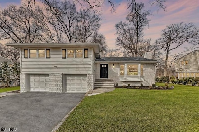 tri-level home featuring a yard, brick siding, driveway, and a chimney