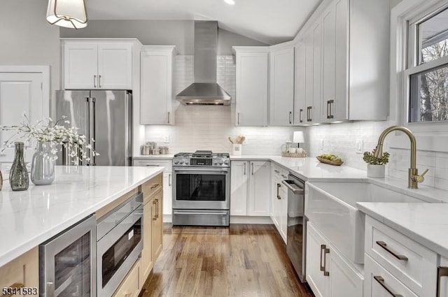 kitchen featuring beverage cooler, wall chimney exhaust hood, appliances with stainless steel finishes, and decorative backsplash