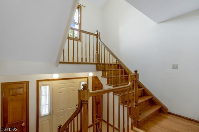 staircase with a high ceiling, wood finished floors, and baseboards