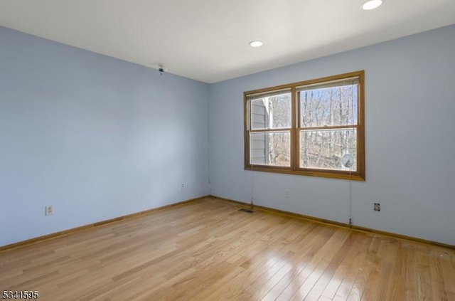 spare room featuring recessed lighting, light wood-style floors, and baseboards