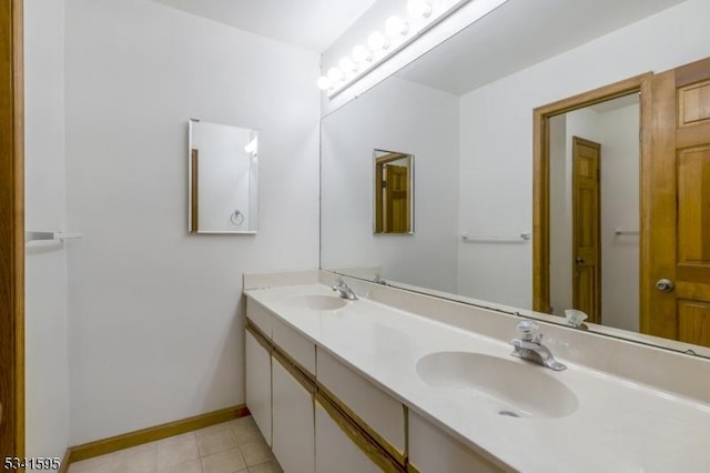 full bathroom with double vanity, baseboards, tile patterned floors, and a sink