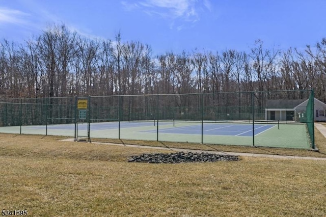 view of tennis court featuring a yard and fence