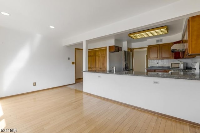 kitchen with visible vents, range hood, stainless steel fridge, range, and white microwave