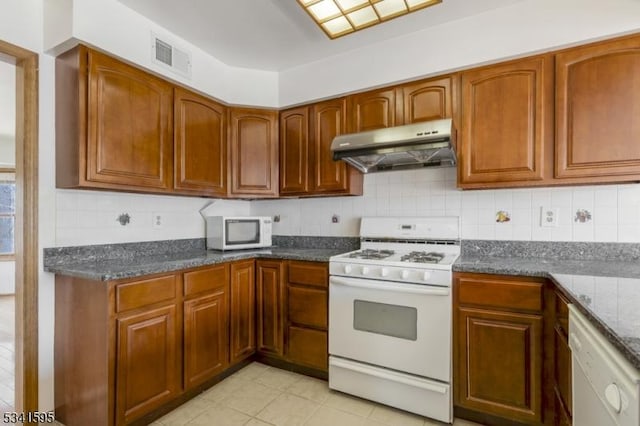 kitchen featuring visible vents, under cabinet range hood, backsplash, white appliances, and brown cabinetry