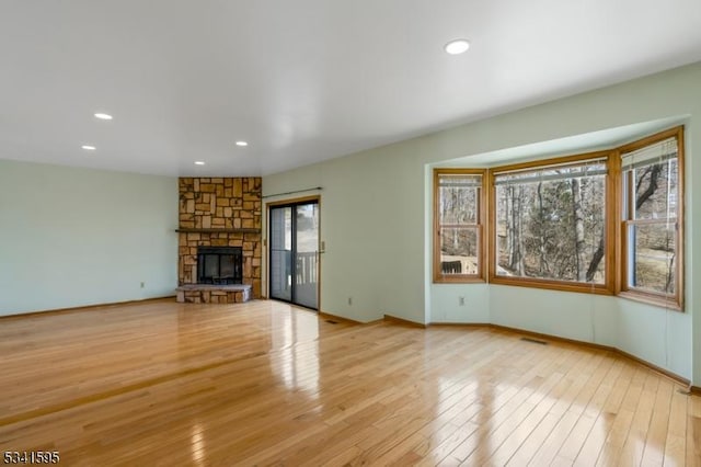 unfurnished living room with visible vents, baseboards, light wood-style flooring, recessed lighting, and a stone fireplace