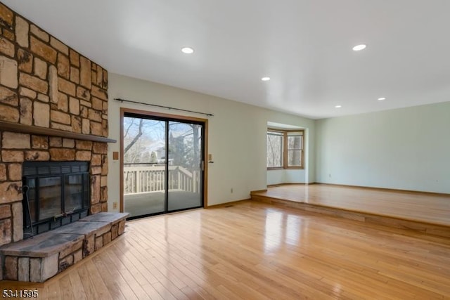 unfurnished living room featuring a stone fireplace, recessed lighting, baseboards, and hardwood / wood-style flooring