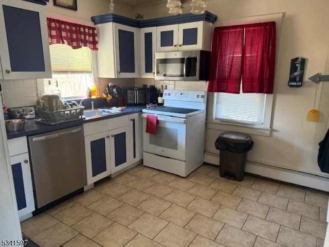 kitchen featuring dark countertops, tasteful backsplash, appliances with stainless steel finishes, and a sink