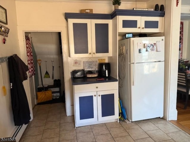 kitchen with dark countertops, white cabinetry, glass insert cabinets, and freestanding refrigerator