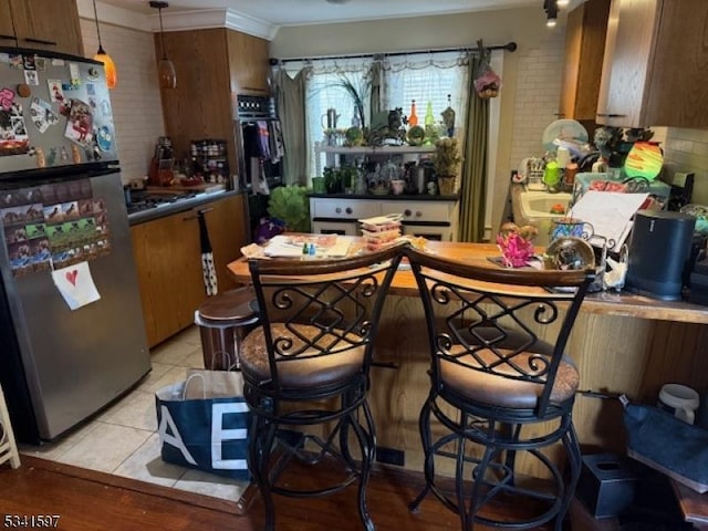 bar with light tile patterned floors, pendant lighting, decorative backsplash, and freestanding refrigerator