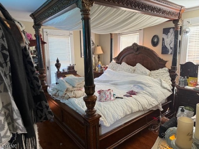 bedroom with ornamental molding and wood finished floors