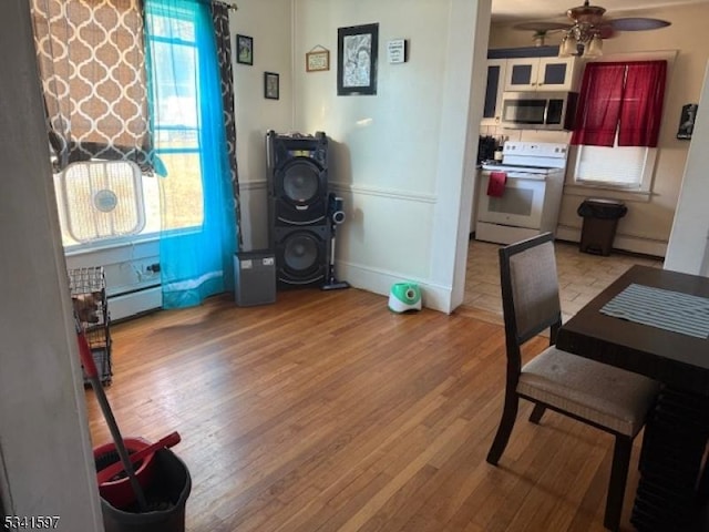 interior space featuring a baseboard heating unit, light wood-type flooring, and a ceiling fan