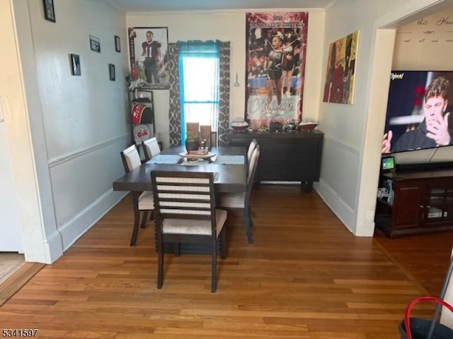 dining space featuring wainscoting, crown molding, and wood finished floors