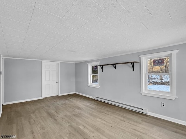 interior space with a textured ceiling, a baseboard radiator, wood finished floors, and baseboards