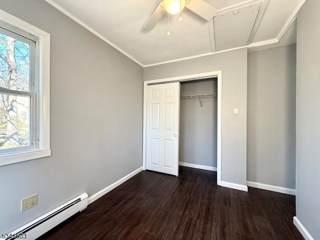 unfurnished bedroom featuring dark wood-type flooring, a baseboard radiator, multiple windows, and baseboards